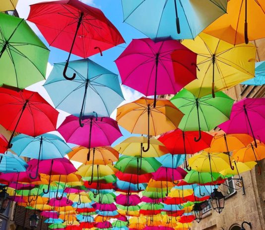 Colorful Umbrellas Float Above a Boutique-Line Passageway In Paris
